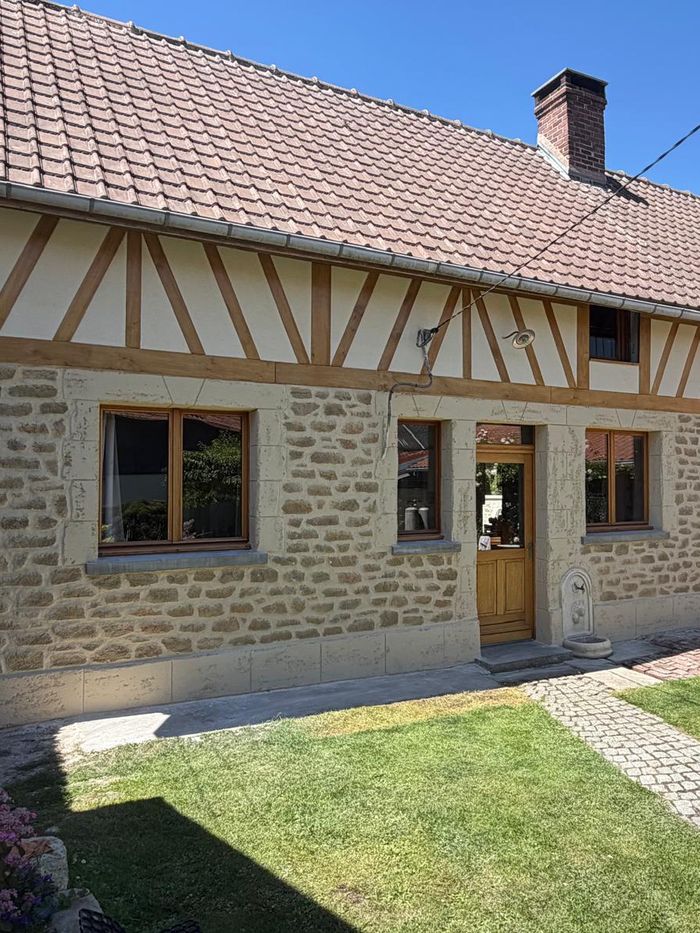 Longère à colombages entièrement rénovée par Robin Façade : soubassement en pierre rejointoyée et pans de bois repris.