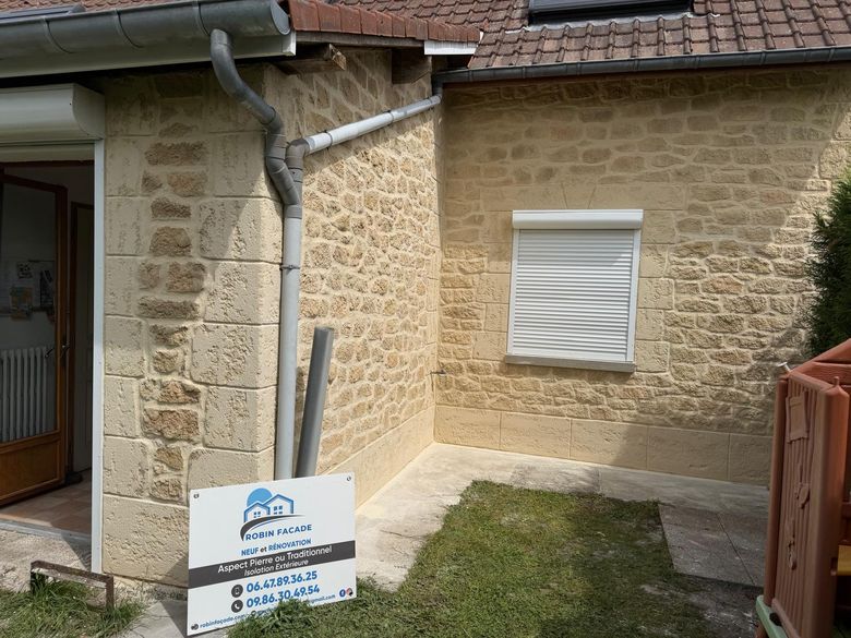 Annexe avec façade finie en aspect pierre et volet roulant blanc.