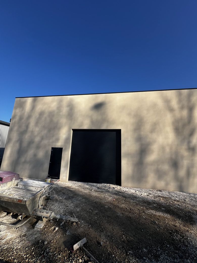 Bâtiment d'activité dont la façade vient d'être enduite, sous un ciel bleu profond.