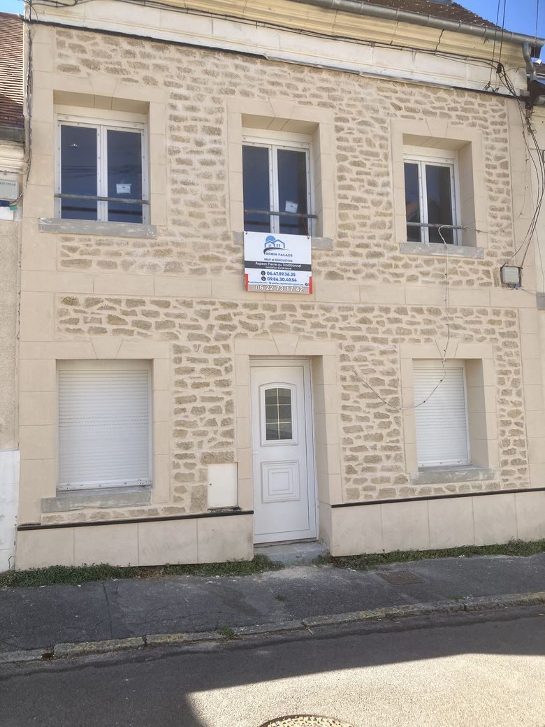 Façade de maison de ville terminée en enduit aspect pierre appareillée.